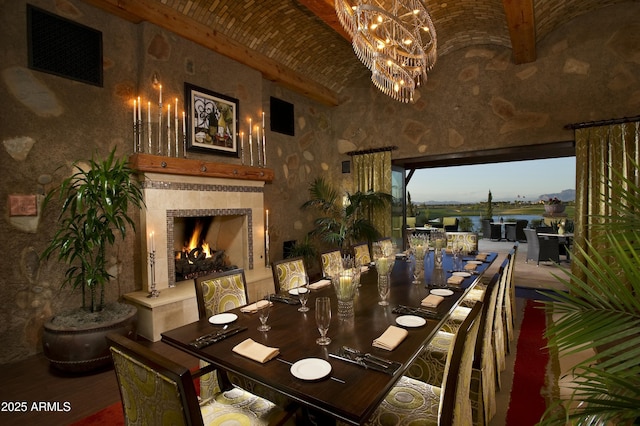 dining area featuring brick ceiling, a tile fireplace, visible vents, and an inviting chandelier