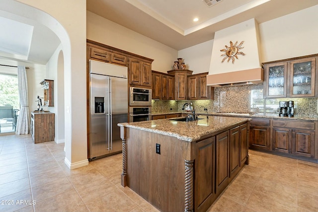 kitchen with a tray ceiling, appliances with stainless steel finishes, a sink, and decorative backsplash