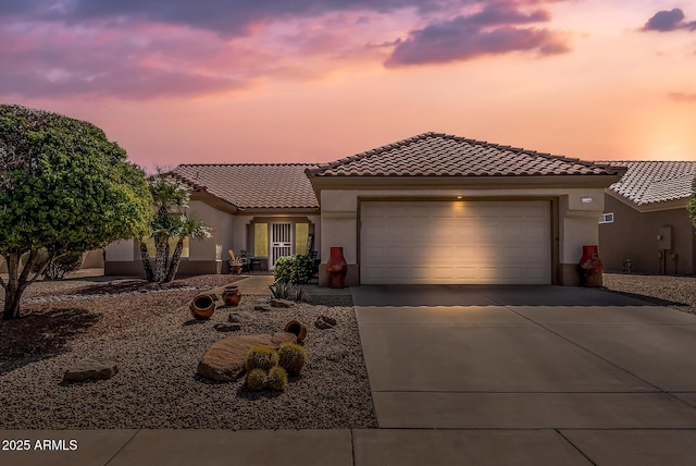 mediterranean / spanish-style house featuring a tile roof, concrete driveway, a garage, and stucco siding