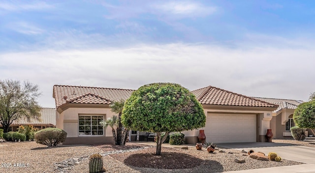 mediterranean / spanish-style home featuring a tiled roof, an attached garage, driveway, and stucco siding