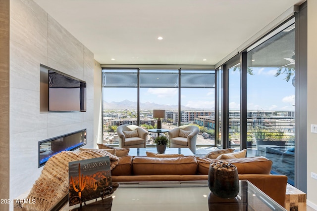 living room featuring a fireplace, tile walls, a healthy amount of sunlight, and floor to ceiling windows