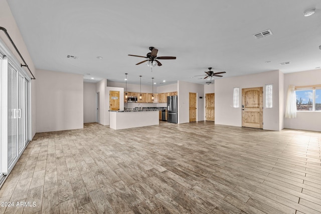 unfurnished living room with light wood-type flooring and ceiling fan