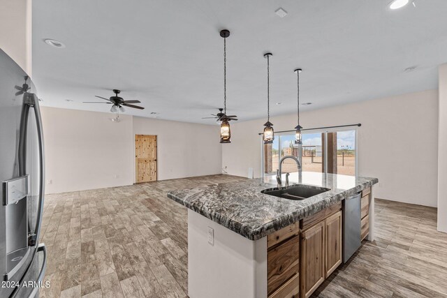 kitchen with ceiling fan, an island with sink, sink, fridge, and light hardwood / wood-style flooring