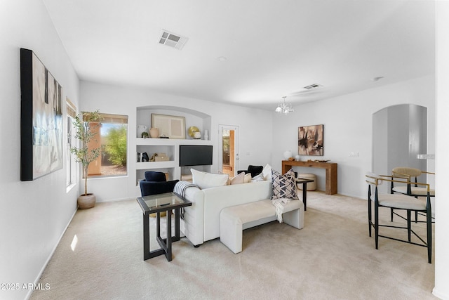 carpeted living room featuring a chandelier