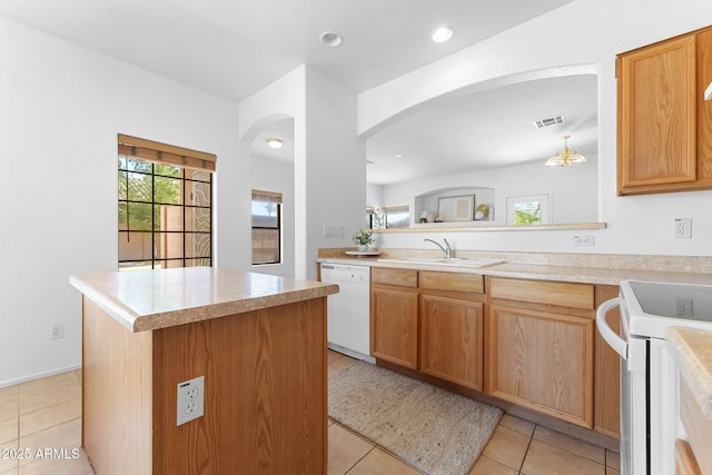 kitchen with light tile patterned flooring, white appliances, a center island, and sink