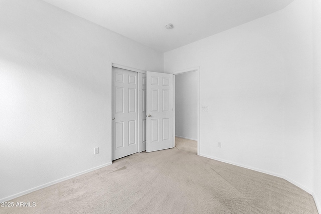 unfurnished bedroom featuring light colored carpet and a closet