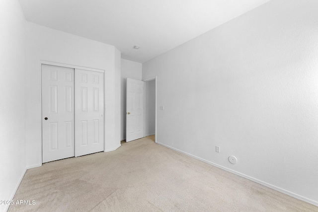 unfurnished bedroom featuring light carpet and a closet