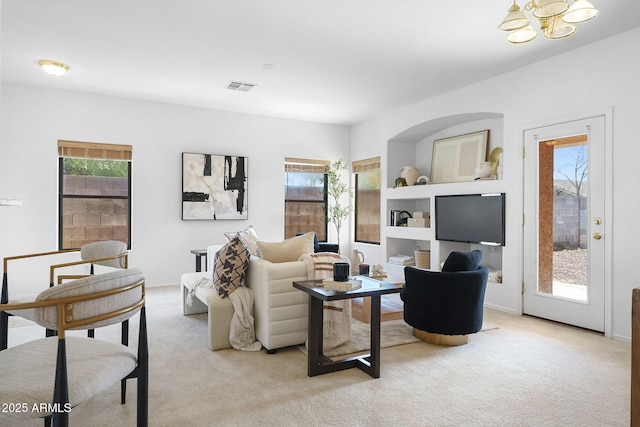 carpeted living room featuring an inviting chandelier and plenty of natural light