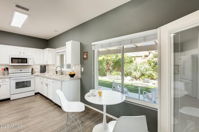 kitchen featuring a sink, visible vents, white appliances, and white cabinets