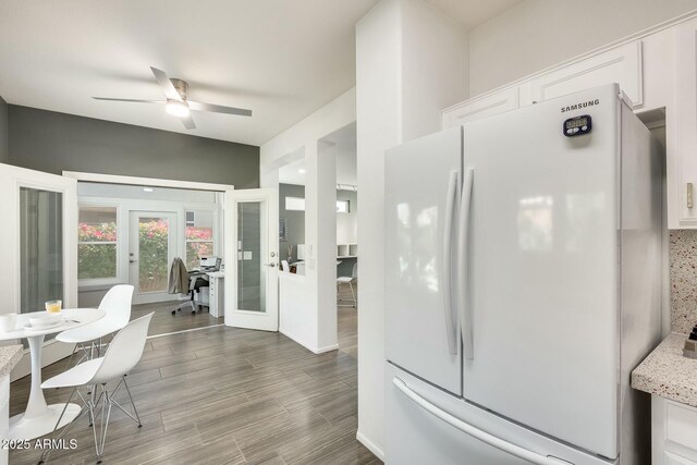 kitchen featuring white cabinetry, freestanding refrigerator, ceiling fan, and wood finished floors