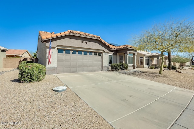 mediterranean / spanish home featuring an attached garage, stucco siding, concrete driveway, a tiled roof, and roof mounted solar panels