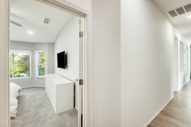 hall with light wood-style floors, baseboards, and visible vents