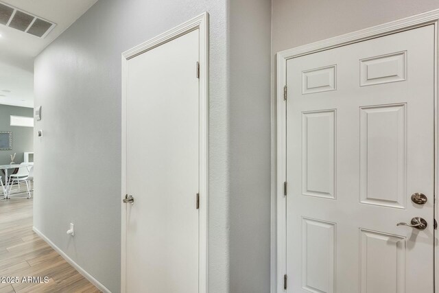 hallway with visible vents, baseboards, and light wood-style floors