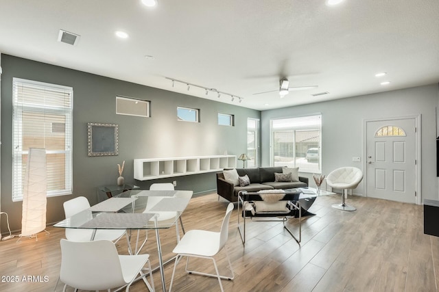 interior space featuring a ceiling fan, track lighting, visible vents, and light wood-type flooring