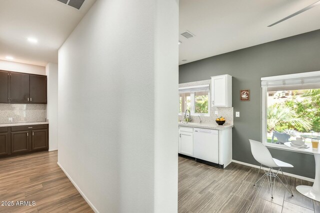 interior space featuring light wood finished floors, visible vents, baseboards, and a sink