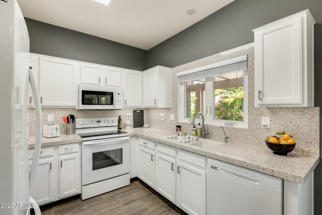 kitchen with a sink, backsplash, wood finished floors, white appliances, and white cabinets