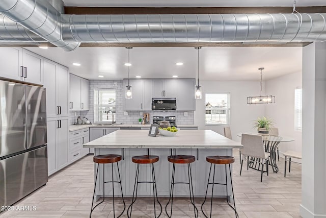 13012 N 36th Dr, Phoenix, AZ 85029 - kitchen with appliances with stainless steel finishes, backsplash, a kitchen breakfast bar, a center island, and recessed lighting