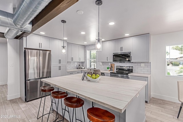 13012 N 36th Dr, Phoenix, AZ 85029 - kitchen featuring appliances with stainless steel finishes, light wood-style floors, a breakfast bar, backsplash, and a kitchen island