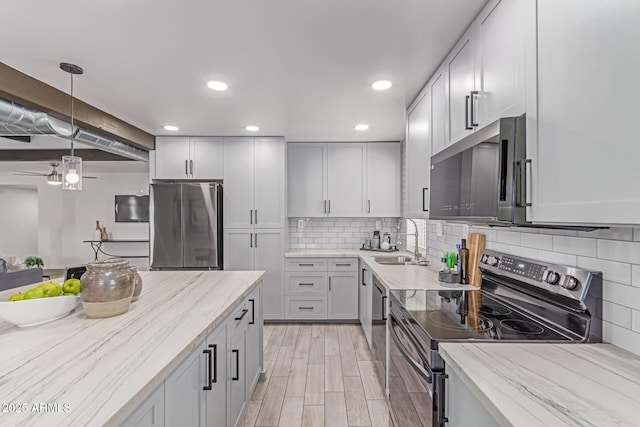 13012 N 36th Dr, Phoenix, AZ 85029 - kitchen featuring appliances with stainless steel finishes, light stone counters, decorative backsplash, hanging light fixtures, and light wood-style floors