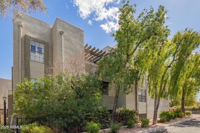 view of side of home with a pergola and stucco siding