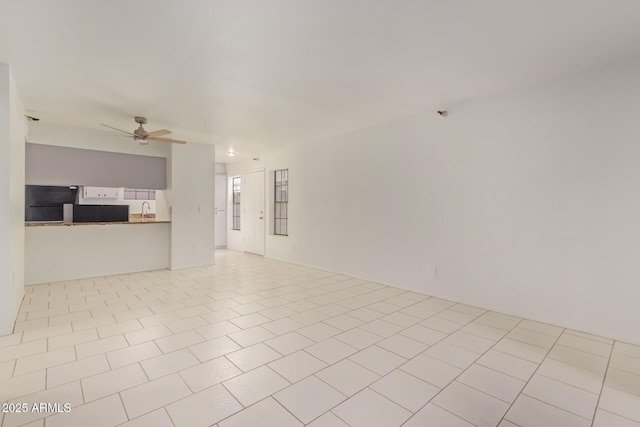 unfurnished living room featuring a sink, a ceiling fan, and tile patterned floors