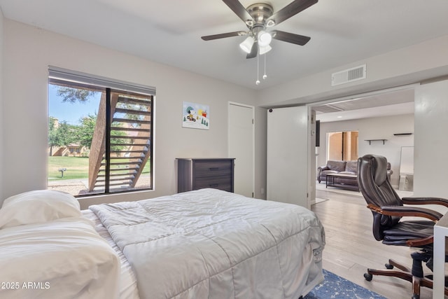 bedroom featuring visible vents, a ceiling fan, wood finished floors, and multiple windows