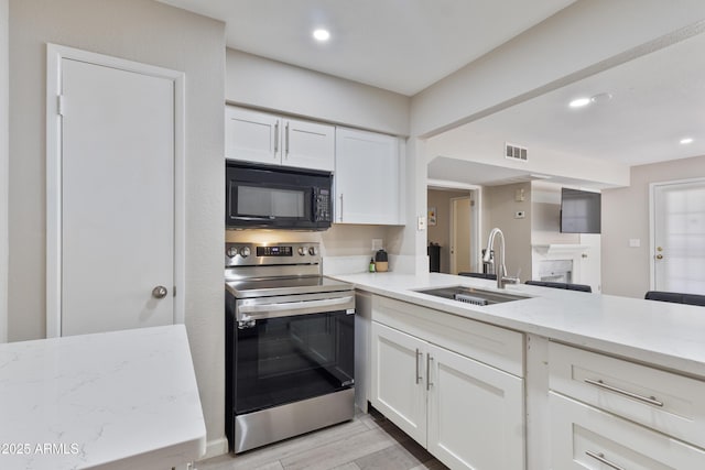 kitchen featuring black microwave, a sink, stainless steel range with electric stovetop, white cabinetry, and visible vents