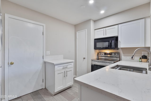 kitchen featuring black microwave, a sink, white cabinets, stainless steel electric stove, and light wood-style flooring
