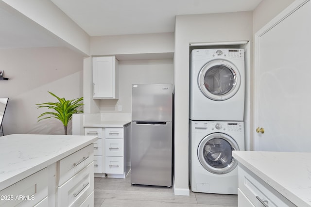 clothes washing area featuring laundry area, stacked washer and dryer, and light wood-style flooring