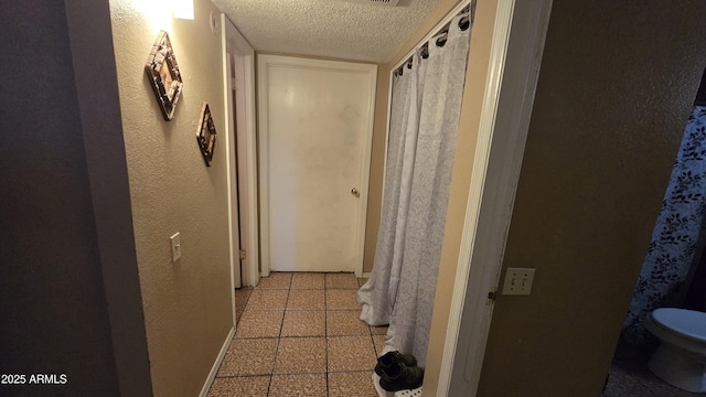 hallway with a textured wall and a textured ceiling