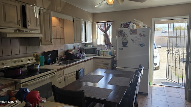 kitchen with under cabinet range hood, white appliances, a sink, light countertops, and tile patterned floors