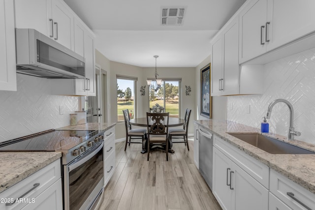 kitchen with light wood-type flooring, visible vents, a sink, stainless steel appliances, and white cabinets