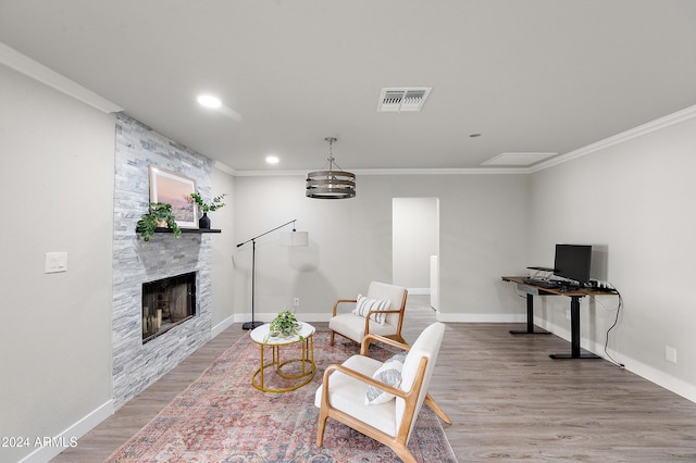 living area with a stone fireplace, hardwood / wood-style flooring, and ornamental molding