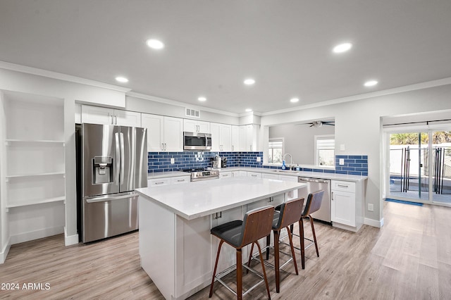 kitchen featuring stainless steel appliances, ceiling fan, white cabinets, a kitchen island, and a breakfast bar area