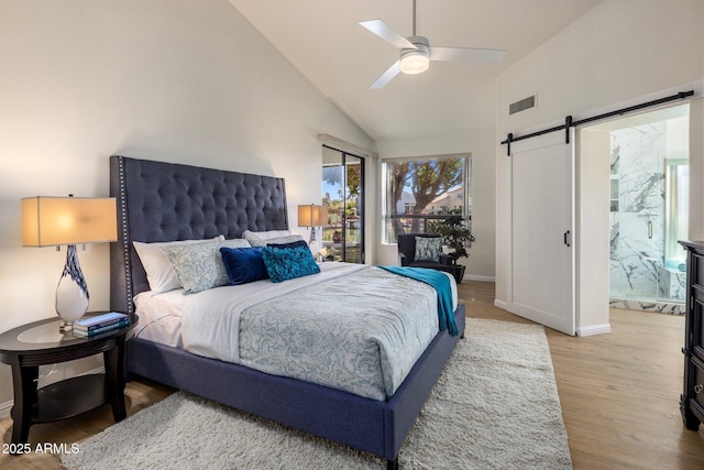 bedroom featuring visible vents, baseboards, ceiling fan, a barn door, and light wood-style flooring