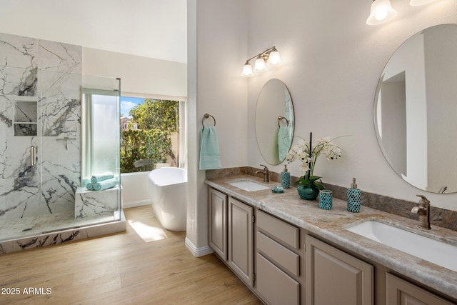 full bathroom featuring a sink, a freestanding tub, a marble finish shower, and wood finished floors