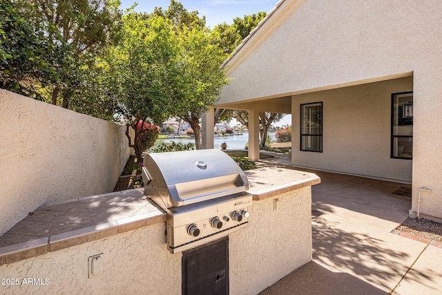 view of patio / terrace featuring a water view, area for grilling, and fence