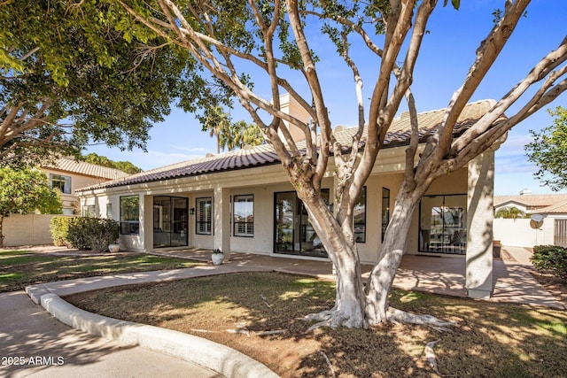 view of front of property featuring a tile roof, fence, and stucco siding