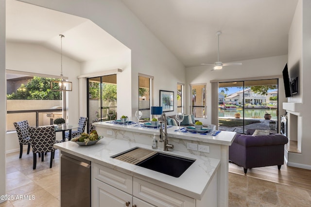 kitchen with lofted ceiling, white cabinets, open floor plan, and a sink