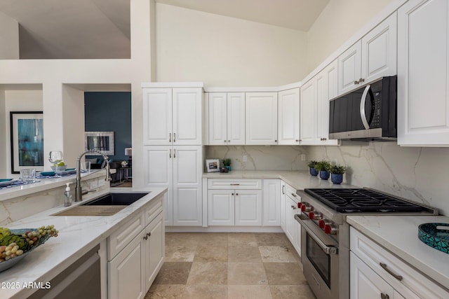 kitchen featuring tasteful backsplash, white cabinets, appliances with stainless steel finishes, and a sink