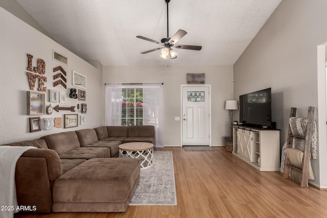 living room with ceiling fan, light wood-type flooring, and a textured ceiling