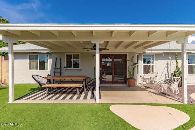 rear view of house featuring a ceiling fan, stucco siding, a patio area, and a yard