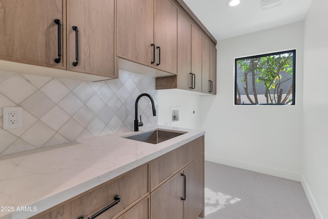 kitchen with baseboards, light stone counters, a sink, backsplash, and recessed lighting