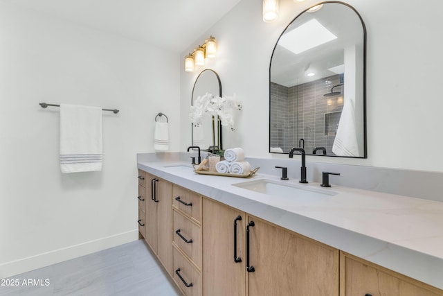 bathroom featuring double vanity, a shower stall, baseboards, and a sink