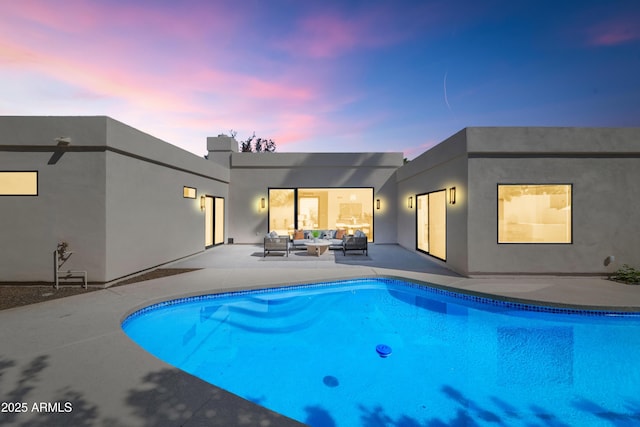 rear view of house with an outdoor pool, a patio area, an outdoor living space, and stucco siding