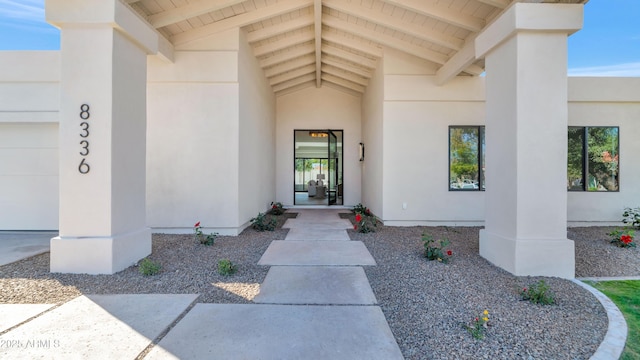 doorway to property featuring an attached garage and stucco siding