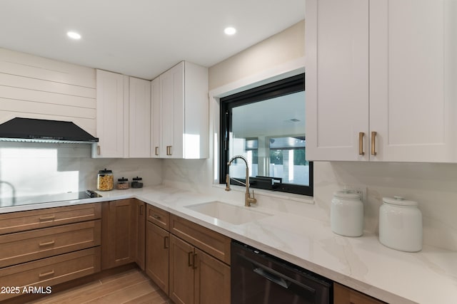 kitchen featuring a sink, white cabinetry, wall chimney exhaust hood, light stone countertops, and black appliances