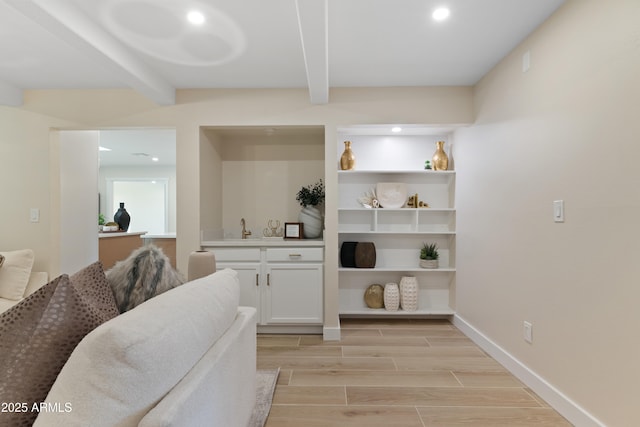 interior space featuring beam ceiling, recessed lighting, wood tiled floor, a sink, and baseboards