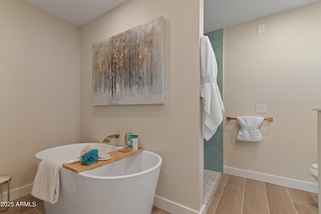 bathroom with wood finish floors, a soaking tub, and baseboards