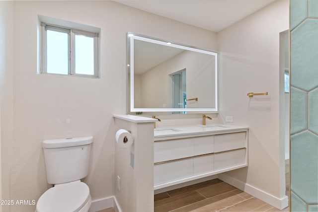 bathroom with wood finish floors, baseboards, a sink, and toilet